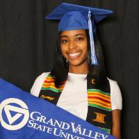 student smiling and holding gvsu flag
